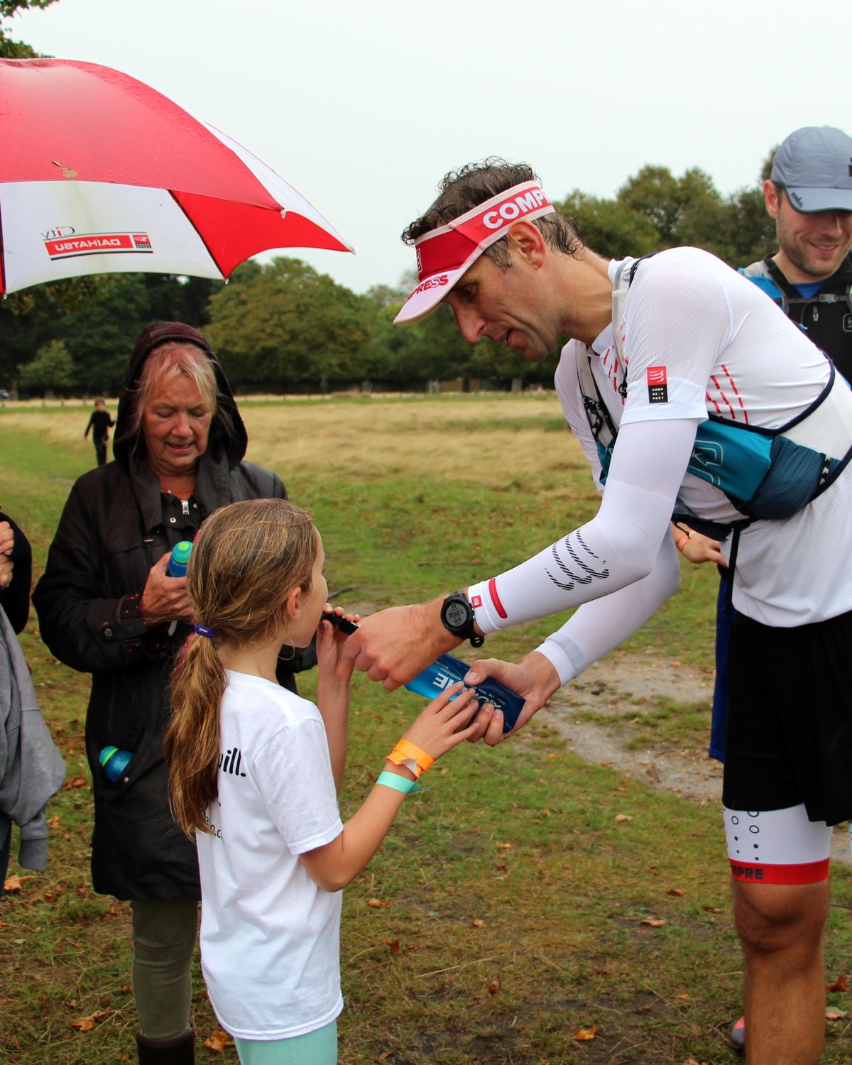 Ben mid-race in the rain, sharing supplies with his young supporter
